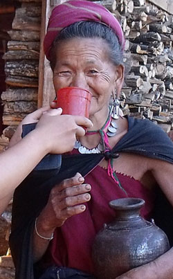 A Kayah woman is shown enjoying traditional millet wine. 
