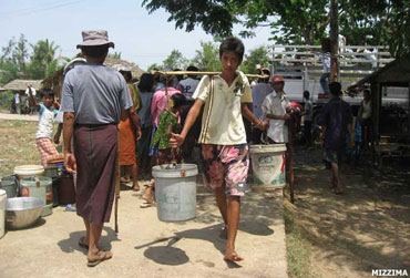 A youth carries water donated by private charities in Dala Township, which bore the heavy burden of severe water shortages in May 2010. Most wells and ponds dried up in the town across the river from central Rangoon, in a drought that left more than 10,000 of the area’s villagers, who usually rely on stored rainwater, dependent on donated water for drinking and hygiene needs. Photo: Mizzima