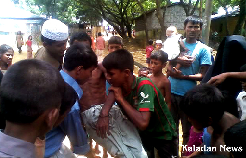 Refugee carrying another elderly refugee to the clinic after local attacked the camp Ktu-06