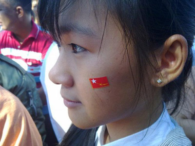 မွန်ပြည်နယ် NLD ရုံးခွဲ ဖွင့်ပွဲ၌ ကြိုဆိုအားပေးနေသူ ရာမည လှပျိုဖြူတစ်ဦး (ဓါတ်ပုံ - အင်တာနက်)