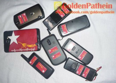 ဧရာဝတီသားများ ဒေါ်စုခရီးစဉ် ကြိုဆိုရေး ကမ်းပိန်း လှုပ်ရှားမှု လက်ကိုင်ဖုန်းများ၌ NLD အလံတံဆိပ် ကပ်ထားပုံ (ဓါတ်ပုံ - IKZ)