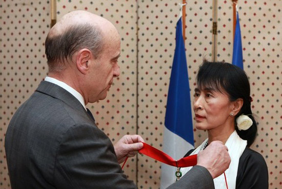 ပြင်သစ်သမ္မတကိုယ်စား ပြင်သစ်နိုင်ငံခြားရေးဝန်ကြီးမှ ဆုတံဆိပ်ကို တပ်ဆင်ချီးမြှင့်ပေးနေပုံ (ဓါတ်ပုံ - အင်တာနက်)