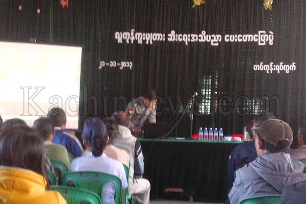 တပ်ကုန်းရပ်ကွက်မှာ ပြုလုပ်တဲ့ လူကုန်ကူးမှုတားဆီးရေး အသိပညာပေးဟောပြေပွဲကို မြစ်ကြီးနားမြို့ အမှတ် (၁) ရဲစခန်းမှူး ဦးမြင့်ကြူက ပို့ချပေးနေပုံ။ တပ်ကုန်းရပ်ကွက်မှာ ပြုလုပ်တဲ့ လူကုန်ကူးမှုတားဆီးရေး အသိပညာပေးဟောပြေပွဲကို မြစ်ကြီးနားမြို့ အမှတ် (၁) ရဲစခန်းမှူး ဦးမြင့်ကြူက ပို့ချပေးနေပုံ။