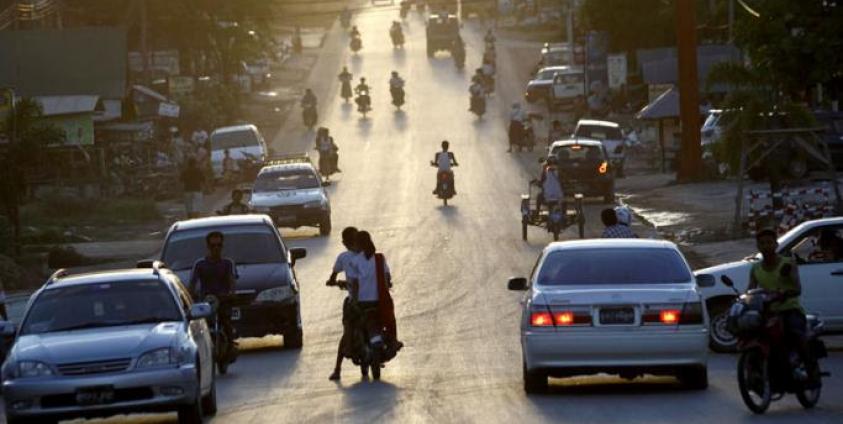 The sun setting down as people drive and ride around a busy road at Myawaddy town, Karen State, eastern Myanmar. Photo: Lynn Bo Bo/EPA