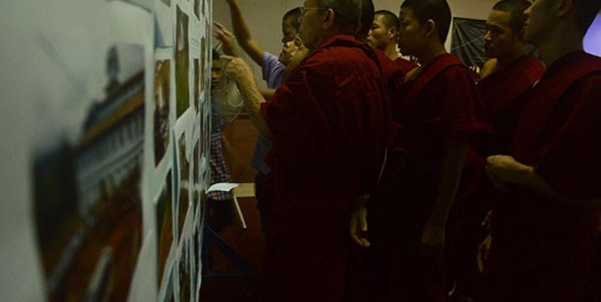 Monks at Thursday’s vigil view a display of photos depicting ongoing military abuses in Shan State. (S.H.A.N)