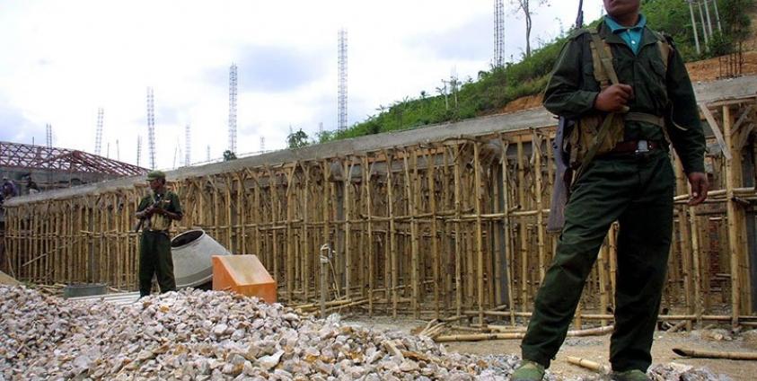 Two Wa soldiers from the United Wa State Army (USWA) stand armed on a construction site. Photo: AFP