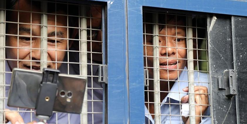 Journalists Aye Nai (L) and Lawi Weng speak to journalists from inside a prisoner transport vehicle outside the courthouse in Hsipaw in Shan State on July 28, 2017. Photo: AFP