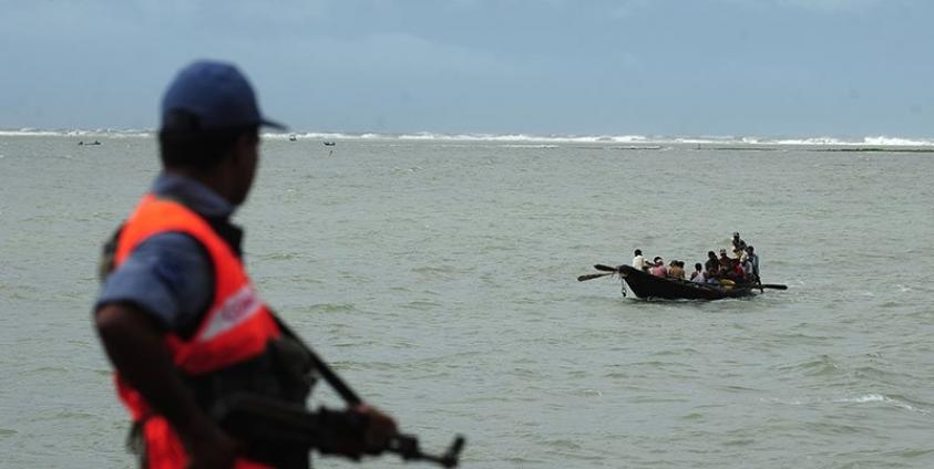 Bangladeshi coast guard watches as a fishing boat passes by in Teknef. Photo: AFP