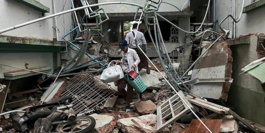 A resident carries belongings over debris next to a damaged building in Naypyidaw on March 28, 2025, after an earthquake in central Myanmar. Photo: Sai Aung Main/AFP