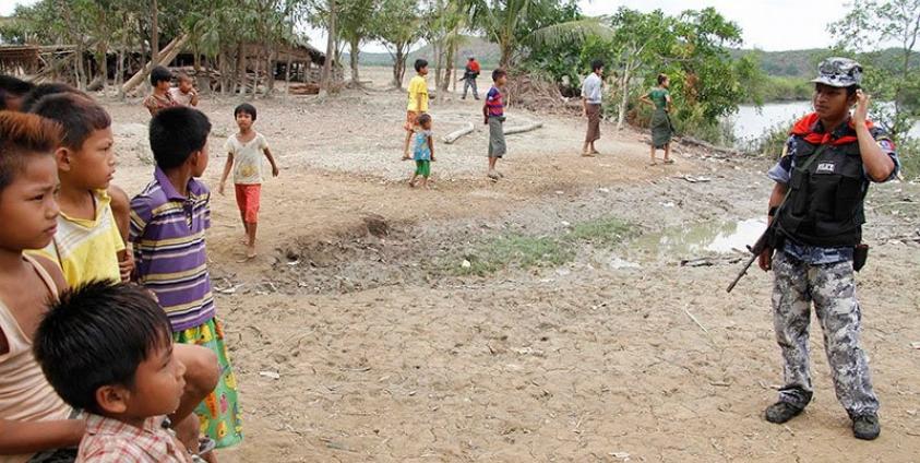 Rakhine children look at an armed guard  at the Si Taung village in Buthee Taung township, northern Rakhine State, Myanmar, 25 April 2016. Photo: Nyunt Win/EPA