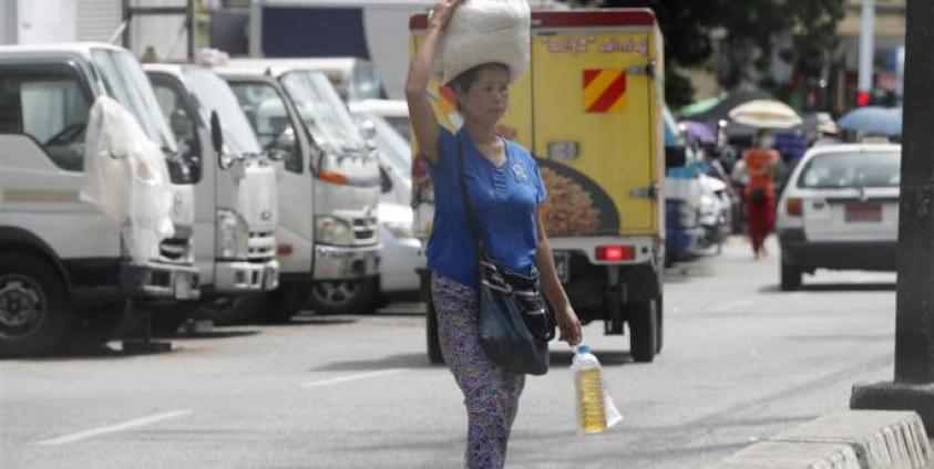 A woman carries rice and cooking oil in Yangon, Myanmar. Photo: EPA