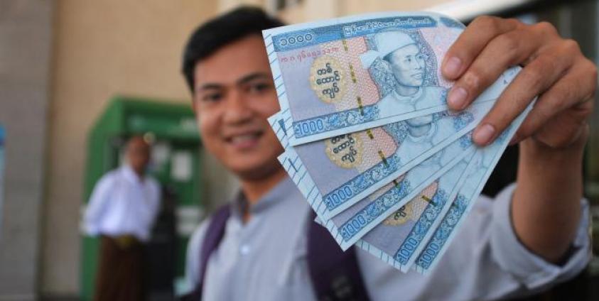 Photo: A man holds new Myanmar kyat banknotes with a portait of the late general Aung San, outside the Myanmar Economic Bank in Naypyidaw on January 7, 2020. Photo: AFP