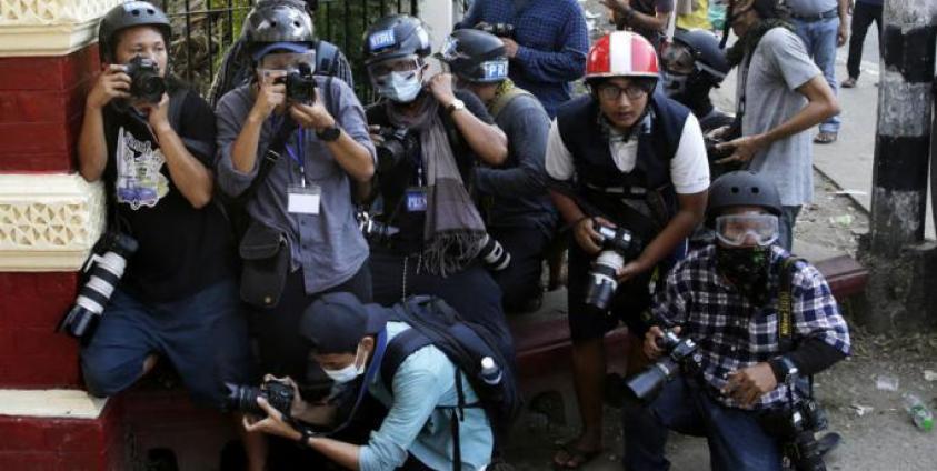 Visual journalists take cover near the entrance of a monastery where military supporters are gathering as they are attacking the protestors and medias and residents, in Yangon, Myanmar, 18 February 2021. Photo: EPA