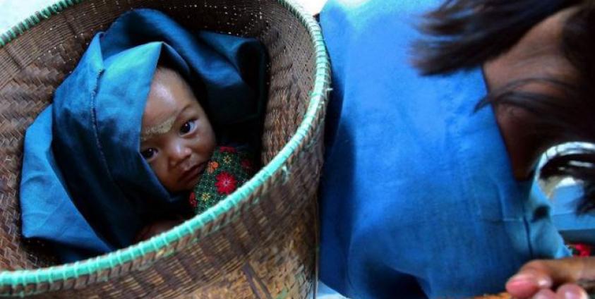 A tribal baby is carried in a basket as her parents head to pick up their rice and yuan payment after labouring in the fields, in north-eastern Myanmar. Photo: EPA