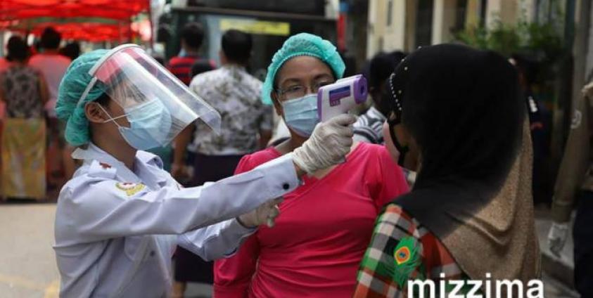  A medical staff member wearing protective gear takes the temperature of a resident while going door-to-door for health check-ups in Yangon on May 22, 2020. Photo: Thet Ko/Mizzima