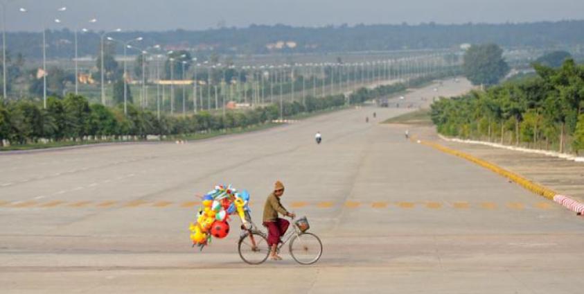 A man rides his bike across a road carrying toys to sell in Myanmar's city of Naypyidaw. Photo: EPA