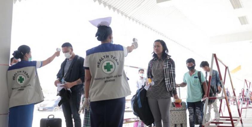 People have their temperatures checked amid concerns over the spread of the COVID-19 coronavirus at the immigration post in Myawaddy near the Thai border on March 23, 2020, as thousands of people crossed from Thailand as the border crossings were due to close because of the growing pandemic. Photo: AFP
