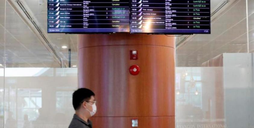 A passenger walks pass a flights information board at the Yangon International Airport in Yangon, Myanmar, 18 March 2020. Photo: Nyein Chan Naing/EPA