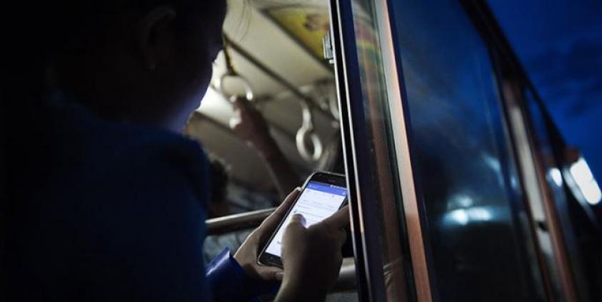 A young woman looks at her Facebook wall while she travels on a bus in Yangon. Photo: AFP