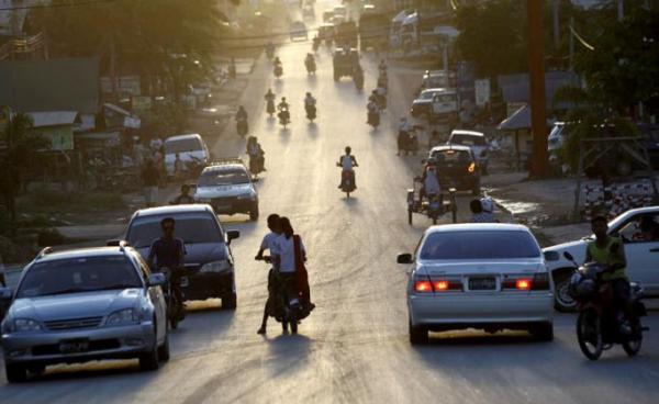 The sun setting down as people drive and ride around a busy road at Myawaddy town, Karen State, eastern Myanmar. Photo: Lynn Bo Bo/EPA