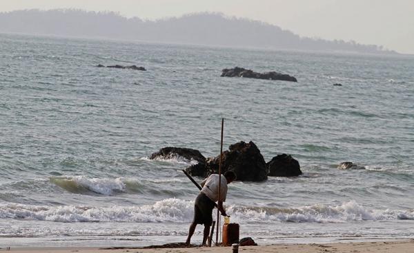 A Rakhine ethnic man collects oil on the shore of Kyauk Phyu, Rakhine state, western Myanmar. Photo: EPA