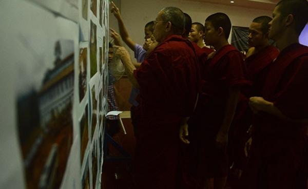 Monks at Thursday’s vigil view a display of photos depicting ongoing military abuses in Shan State. (S.H.A.N)