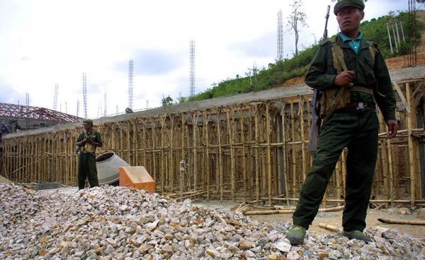 Two Wa soldiers from the United Wa State Army (USWA) stand armed on a construction site. Photo: AFP 