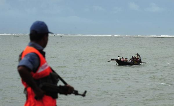 Bangladeshi coast guard watches as a fishing boat passes by in Teknef. Photo: AFP