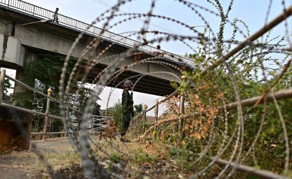 Thai military personnel stands guard overlooking the Moei river on the Thai side, near the Tak border checkpoint with Myanmar, in Thailand’s Mae Sot district on April 11, 2024. Myanmar junta troops have withdrawn from a major trade hub near the Thai border following days of clashes, an ethnic armed group told AFP on April 11, 2024, dealing a further blow to the embattled military. (Photo by MANAN VATSYAYANA / AFP)