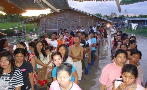 The migrant workers line up outside of a flooded camp in Chiang Mai