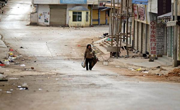 (File) A woman walks along a deserted road in self-administered Kokang capital Laukkai, northern Shan State, Myanmar, 16 February 2015. Photo: Lynn Bo Bo/EPA