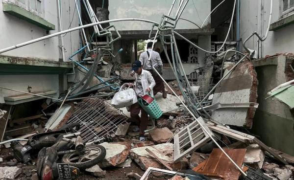 A resident carries belongings over debris next to a damaged building in Naypyidaw on March 28, 2025, after an earthquake in central Myanmar. Photo: Sai Aung Main/AFP