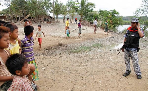 Rakhine children look at an armed guard  at the Si Taung village in Buthee Taung township, northern Rakhine State, Myanmar, 25 April 2016. Photo: Nyunt Win/EPA