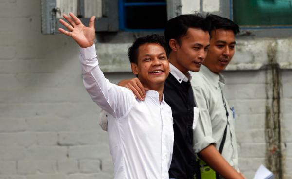 Weekly Eleven ဂျာနယ်ပါ ဆောင်းပါးရေးသားခဲ့သူ ဖြိုးဝေ (လက်ပြနေသူ) အား တာမွေရဲစခန်းသို့ လာရောက်အဖမ်းခံရာတွင် တွေ့မြင်ရစဉ်။ဓာတ်ပုံ - EPA-EFE/LYNN BO BO