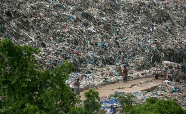 People walk past a garbage dump on the outskirts of Yangon on June 5, 2019. Photo: Sai Aung Main/AFP
