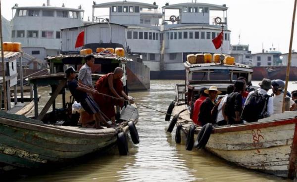 A Buddhist monk and a man pull a rope of the boat at the Chindwin river in Monywa, Sagaing Division, Myanmar. Photo: Nyein Chan Naing/EPA