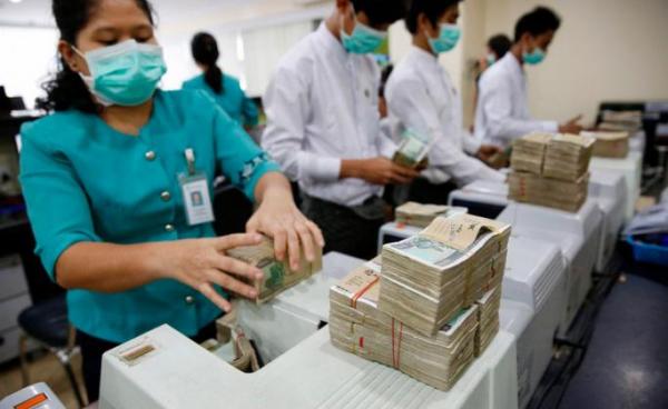 Staff members of the Asia Green Development Bank count Myanmar Kyat notes with machines at Sule branch office, in Yangon, Myanmar, 14 December 2016. Photo: EPA