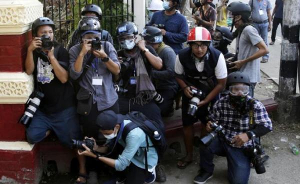 Visual journalists take cover near the entrance of a monastery where military supporters are gathering as they are attacking the protestors and medias and residents, in Yangon, Myanmar, 18 February 2021. Photo: EPA