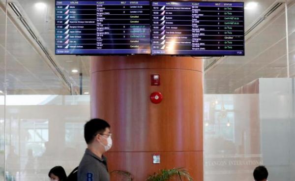 A passenger walks pass a flights information board at the Yangon International Airport in Yangon, Myanmar, 18 March 2020. Photo: Nyein Chan Naing/EPA