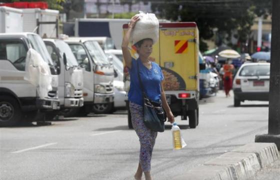 A woman carries rice and cooking oil in Yangon, Myanmar. Photo: EPA