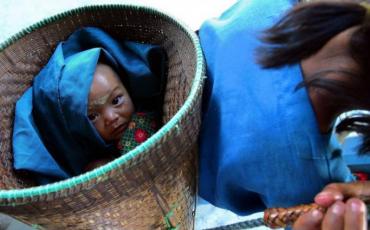 A tribal baby is carried in a basket as her parents head to pick up their rice and yuan payment after labouring in the fields, in north-eastern Myanmar. Photo: EPA